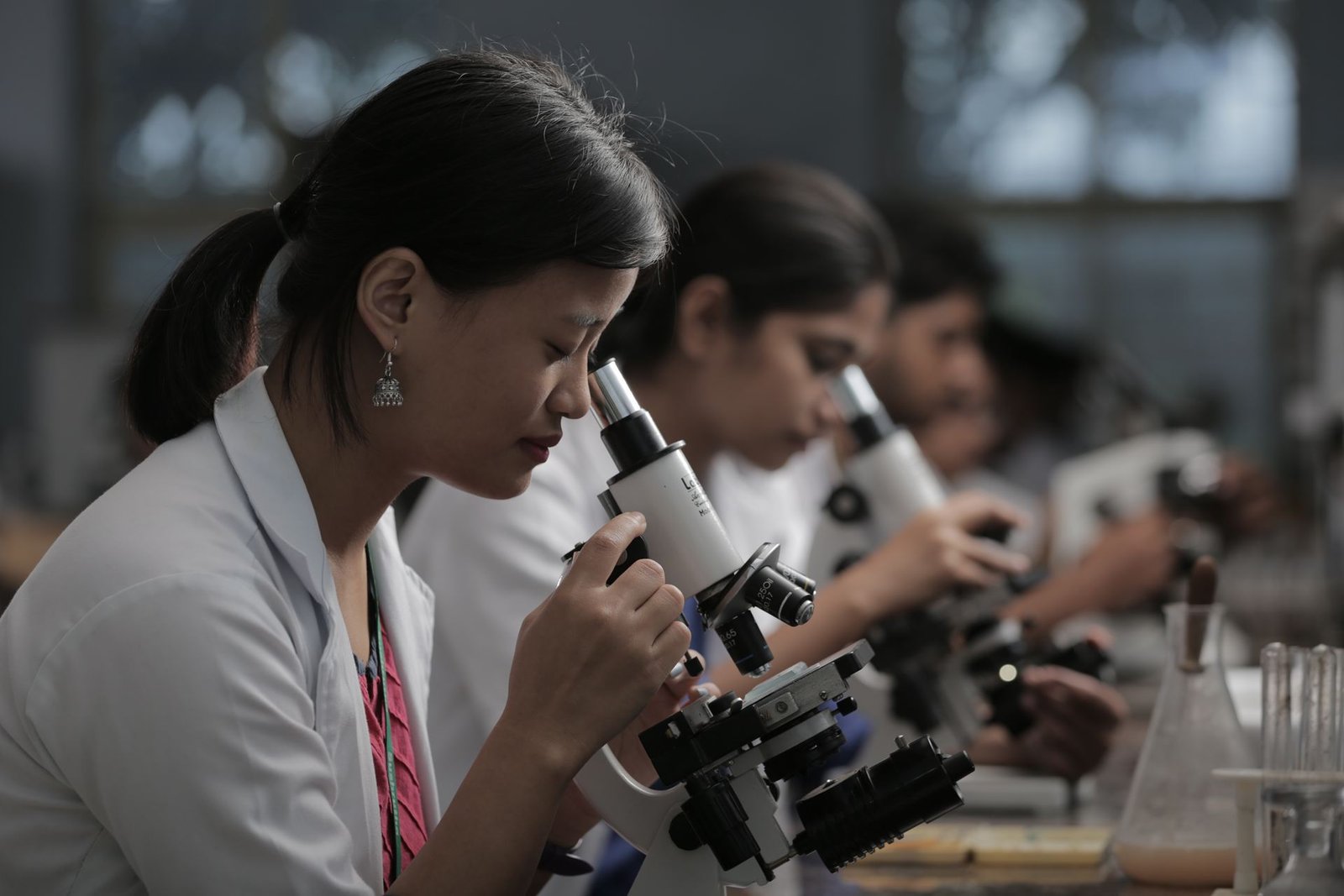 Microscope in a modern laboratory, set against traditional herbs and scrolls.